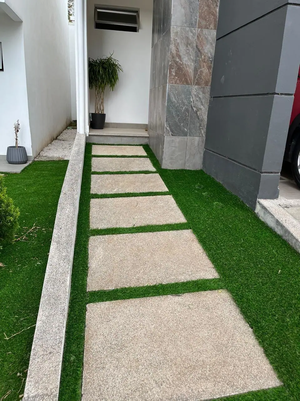 Después: sendero moderno con césped artificial entre huellas de concreto, por Jardines BR