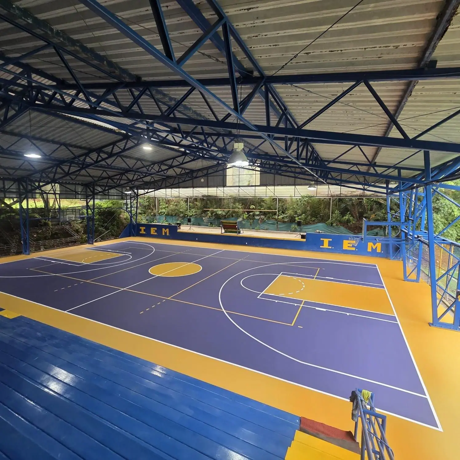 Cancha multiuso techada con superficie deportiva morada y amarilla instalada por Jardines BR