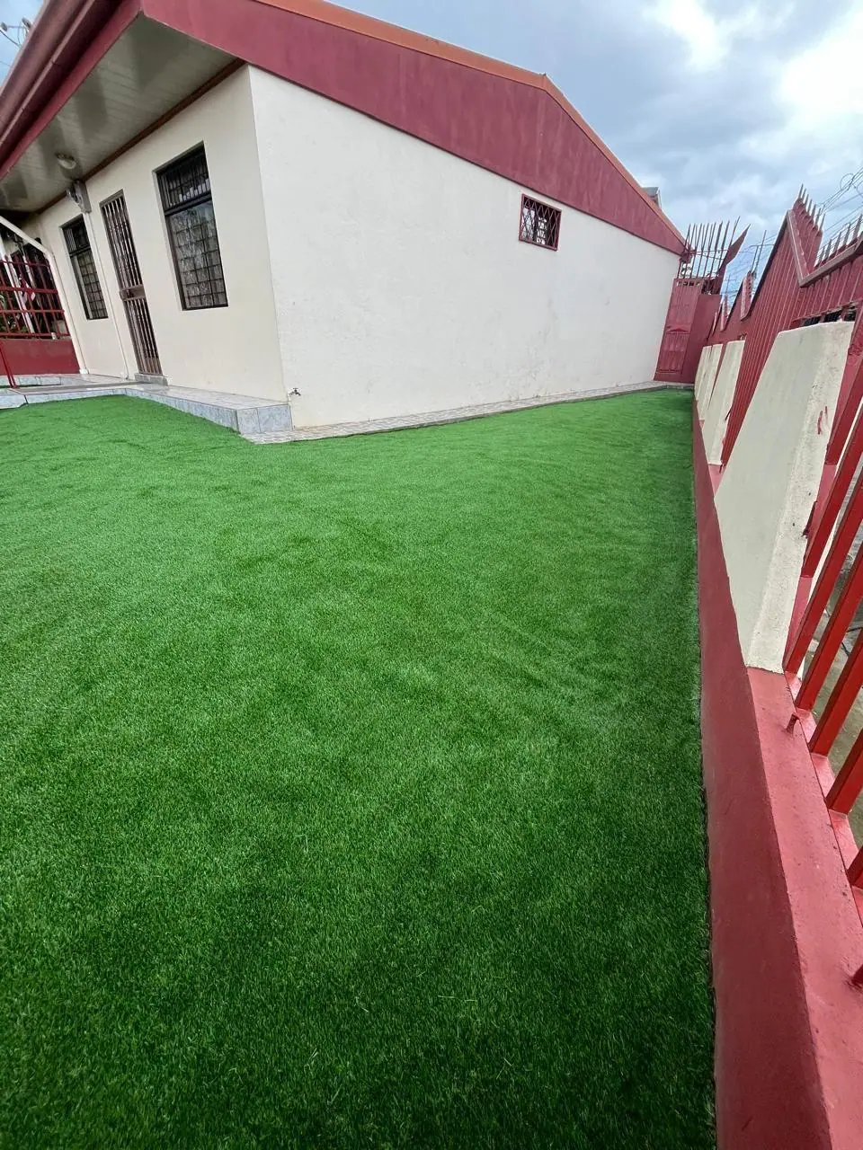 Jardín frontal con césped artificial en casa residencial