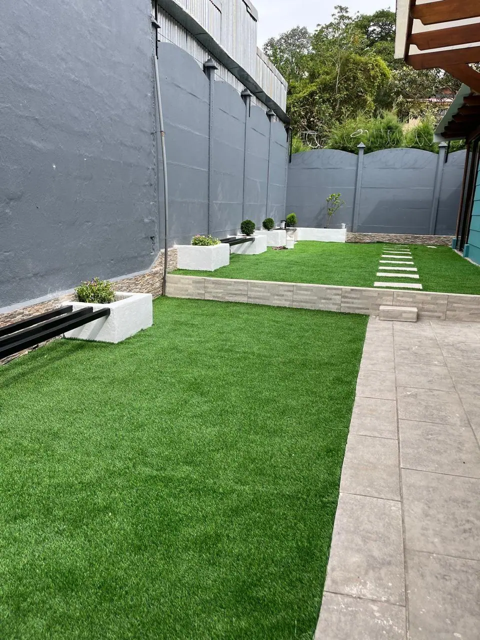 Césped artificial residencial con jardineras y huellas de paso, instalado por Jardines BR